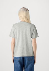 Camiseta gris de manga corta con un corte relajado. Material de mezcla de algodón, diseño de cuello redondo. Textura suave, sin patrones o acentos visibles.