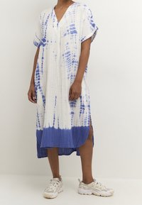 Vit och blå batikmönstrad klänning med V-hals, korta ärmar och sidofickor. Tillverkad av lättviktig tyg med en texturerad finish vid fållen.