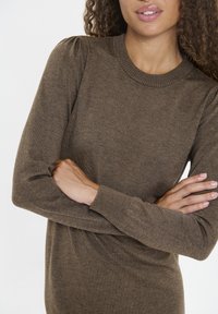 Brauner, langärmliger Pullover mit geripptem Halsausschnitt und puffartigen Schulterdetails. Weiche Textur mit eng anliegenden Ärmeln.