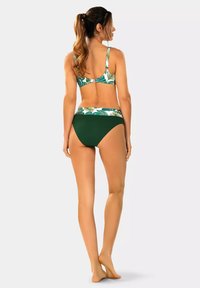 Zielono-biały bikini z liściastym wzorem na górnej części i jednolitymi zielonymi majtkami. Regulowane ramiączka i bezszwowy pas.