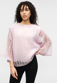 Ανοιχτό ροζ, πλεκτό πουλόβερ με ανοιχτή ύφανση, φαρδιά μανίκια και χαλαρή εφαρμογή. Το υφασμένο νήμα δημιουργεί μια αναπνεύσιμη, στρωματοποιημένη εμφάνιση.