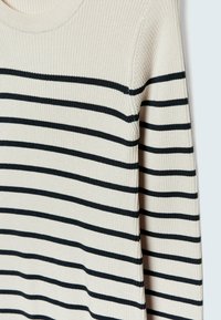 Maglione a coste color crema con strisce orizzontali blu navy. Presenta un collo rotondo e maniche lunghe, evidenziando un tessuto testurizzato.