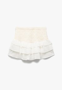 Falda blanca con una capa superior texturizada y volantes en la parte inferior, confeccionada con materiales ligeros. Los detalles son suaves y fluidos.