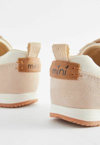Helle rosa Wildlederschuhe für Kinder mit weißen Netz-Details, einem beigefarbenen Lederetikett und strukturierten Zuglaschen auf der Rückseite. Weiße Gummisohle.