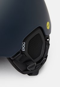 Casque de couleur bleu marine mat, avec une maille de ventilation noire, un autocollant jaune Mips et des sangles réglables pour un ajustement sécurisé.
