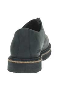 Scarpa in pelle nera con design a taglio basso, punta rotonda, suola texturizzata e intersuola in sughero. Presenta cuciture visibili e logo del marchio sul lato.