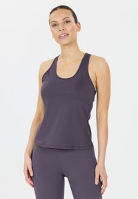 Lila Sporttanktop mit Racerback-Design, glatter Textur und dezentem Branding in der Mitte. Kombiniert mit passenden, figurbetonten Leggings.