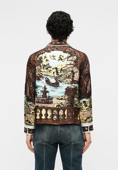 Πίσω όψη ατόμου που φοράει πουκάμισο με λεπτομερή εκτύπωση γόνδολας σε ποτάμι, συντριβάνια, αγάλματα και δέντρα σε γραφική κηπουρική διαμόρφωση.