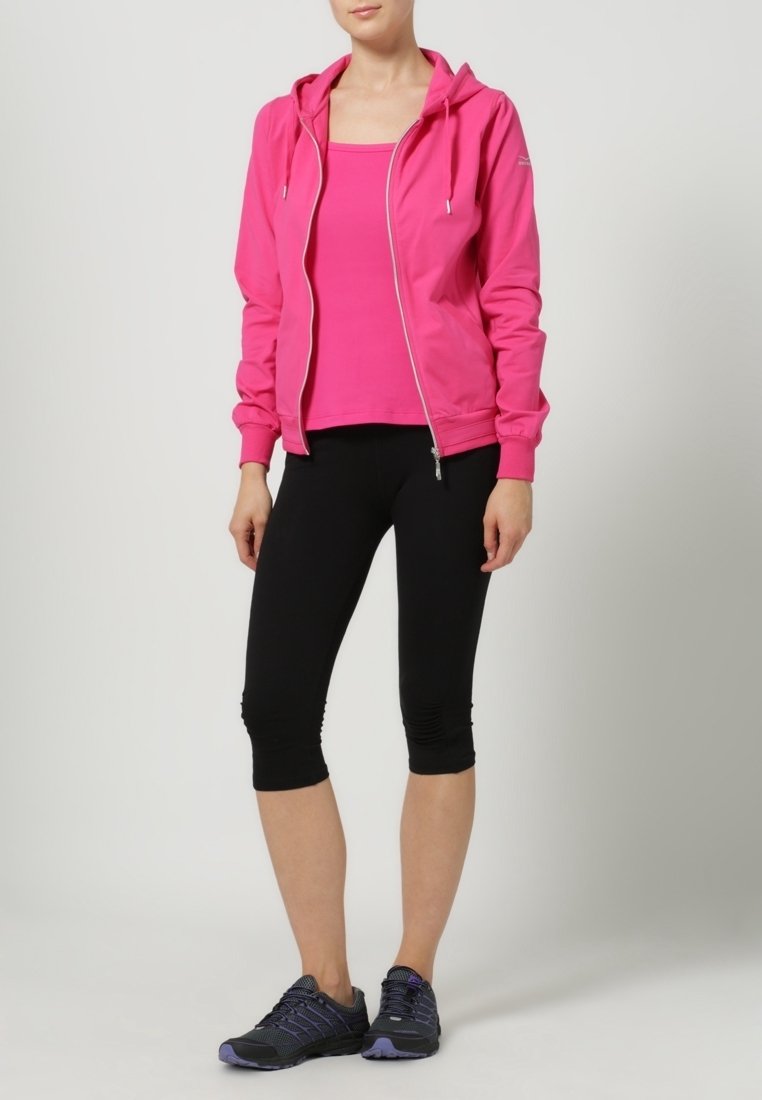 Vaaleanpunainen vetoketjullinen huppari, vaaleanpunainen toppi, mustat capri-legginssit ja mustat urheilukengät. Sileä kangas, istuva malli, nyörivivahtein.