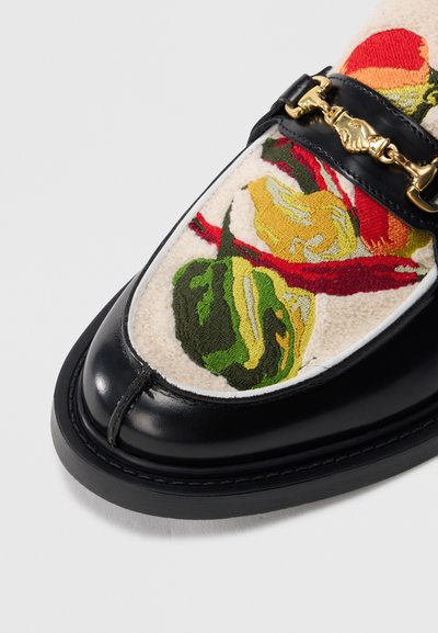 Μαύρα δερμάτινα μοκασίνια με κεντητό floral μοτίβο σε μπεζ ύφασμα στο επάνω μέρος και χρυσή αλυσίδα διακόσμησης στο λουράκι. Υφή με ανάγλυφη επιφάνεια.