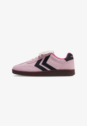 Pink suede sneaker with dark brown sole, black double chevron design, white laces, and pink inner lining.