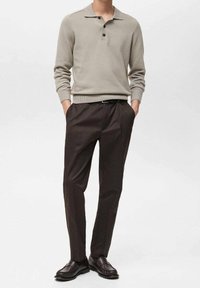 Jasnoszary dzianinowy polo z trzema guzikami, w połączeniu z ciemnobrązowymi spodniami eleganckimi i ciemnymi skórzanymi butami. Prosty, nowoczesny krój i design.
