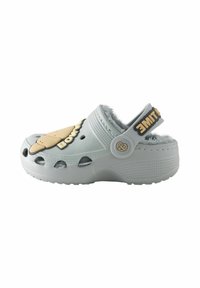 Light grey clog with fuzzy lining, ventilation holes, and a tan ice cream graphic. Features a black strap with text and a circular accent.
