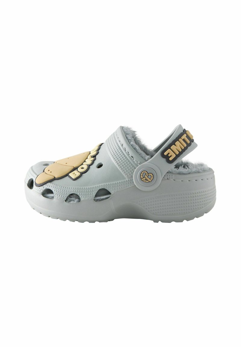 Light grey clog with fuzzy lining, ventilation holes, and a tan ice cream graphic. Features a black strap with text and a circular accent.