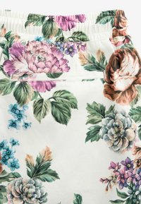 Tessuto con motivo floreale su sfondo bianco, caratterizzato da grandi fiori rosa, viola e blu, e foglie verdi. Inclusa una vita elastica.