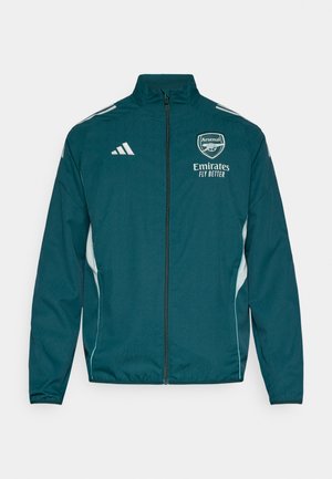 Tüürissaarene spordijakk lukuga, valgete detailidega ja "Arsenal" logoga. Valmistatud kerge kaaluga materjalist, omab kõrget kraed ja elastseid mansette.