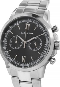 Silberner Edelstahlzeitanzeiger mit schwarzem Zifferblatt. Besitzt kräftige Stundenziffern, einen Tachymeter und zwei Hilfszifferblätter, gesichert mit einem Metallarmband.