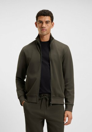 Oliven grøn, lynlåset jakke med høj krave, blødt stof, ribbede manchetter og en matchende sort inderskjorte. Minimalistisk design, atletisk pasform.