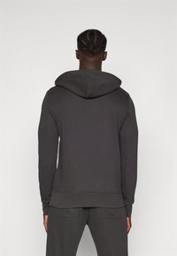 Felpa con cappuccio in misto cotone grigio scuro, caratterizzata da una vestibilità comoda, polsini e orlo a costine, e un design semplice e privo di decorazioni.