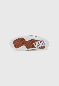 Semelle de sneaker blanche avec une section en caoutchouc brun. Présente un motif de grip texturé et le logo "VANS" bien en vue. Design épuré dans l'ensemble.
