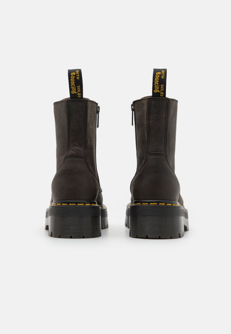Stivali ankle in pelle marrone con suole in gomma nera, cuciture gialle lungo il bordo e una linguetta sul retro. Cerniere laterali per la chiusura.