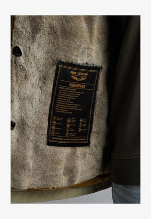 Hættejakke med funktionalitet, blød grå kunstpelsforing, sort plejelabel og grøn yderstof med aftagelig polstring.