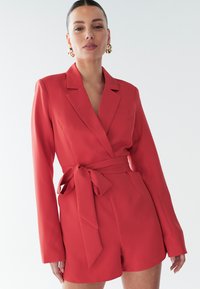 Raudonas švarko modelis su ilgomis rankovėmis, liemenį apjuosia diržas, vienas krūtin�ės kišenė. Lygi medžiaga su subtilia tekstūra ir pritaikytu dizainu.