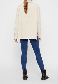 Beige korduray skjortjacka med avslappnad passform, ryggveck och knappmanschetter, ihop med mörkblå skinnyjeans och svarta ankelstövlar.