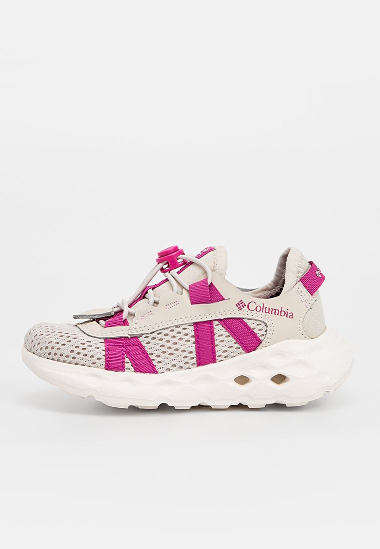 Zapatilla deportiva color beige claro con acentos en rosa, parte superior de malla, cordones elásticos, suela acolchada con recortes y marca Columbia en el lateral.