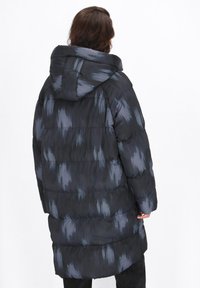 Schwarze Pufferjacke mit grauem Pinselstrichmuster, ausgestattet mit Kapuze, gerippten Bündchen und einer gesteppten Textur für Isolation und Wärme.