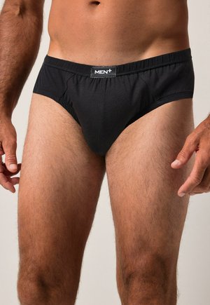 Schwarze Baumwollunterhose mit elastischem Bund, ausgestattet mit einer Fronttasche und einem kontrastierenden Logoetikett über dem Bund. Glatte Textur.