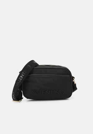 Borsa a spalla in nylon nero con logo in rilievo, chiusura con zip e tracolla regolabile con marchio ripetuto. Forma rettangolare compatta.
