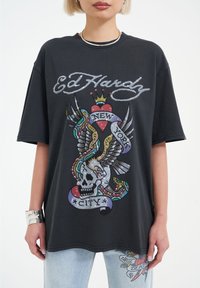 Black oversized t-shirt featuring a colorful, bedazzled graphic of a skull with wings, hearts, and a banner reading "New York City."