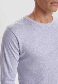 Grå langærmet t-shirt lavet af letvægtsstof med rund halsudskæring og subtil tekstur, med tætsiddende ærmer og en glat overflade.