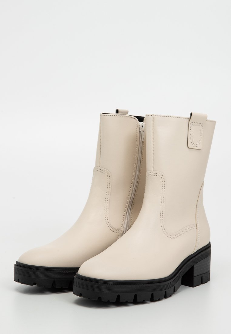 Beige Leder-Stiefeletten mit einem seitlichen Reißverschluss, Blockabsatz und Gummisohle. Merkmale sind minimale Nähte und eine Zuglasche am Schaft.
