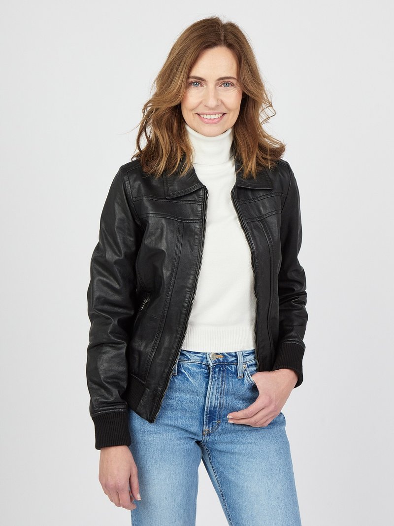 Schwarze Lederjacke mit taillierter Passform und gerippten Bündchen. Getragen über einem weißen Rollkragenpullover, kombiniert mit hochgeschnittenen blauen Jeans.