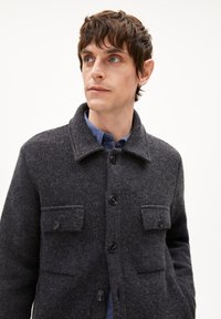 Dunkelgraue Wollmischungjacke mit Kragen, vorderen Taschen und Knopfverschluss. Strukturiertes Gewebe mit schwarzen Knöpfen und lockerer Passform.