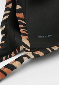 Černá tkanina s tygřím vzorem v béžové a oranžové barvě. Obsahuje logo "TEZENIS" a má hladkou texturu s detaily švů.