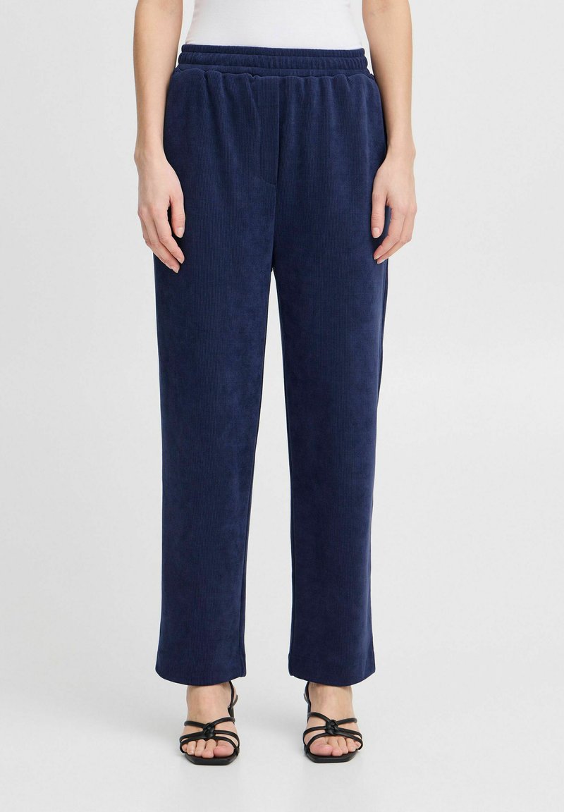 Pantalons en velours côtelé navy avec une taille élastique, coupe droite et poches latérales. Texture douce avec un motif à nervures subtil.
