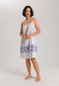 Camisa de noche blanca sin mangas con un escote fruncido y bordado floral azul a lo largo del dobladillo. Tela ligera con una textura suave.