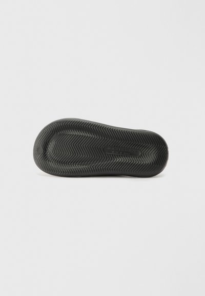Semelle de chaussure en caoutchouc noir avec un motif en chevrons pour l'adhérence. Texture lisse avec un bout arrondi et un minimum de marquage sur la surface.