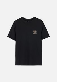 T-shirt en coton noir avec un col rond et des manches courtes. Présente un petit motif coloré sur le côté gauche de la poitrine.