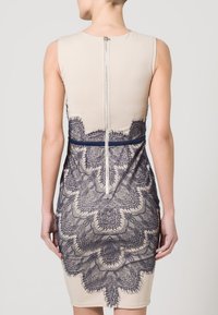 Béžové šaty s námořnickými krajkovými detaily na zadní straně, nabízející upnutý střih, zapínání na zip a hladký povrch.