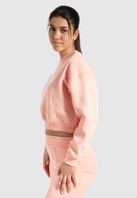 Roze cropped sweatshirt van zachte stof, met een ronde halslijn en geribde boorden. Gecombineerd met bijpassende joggers.