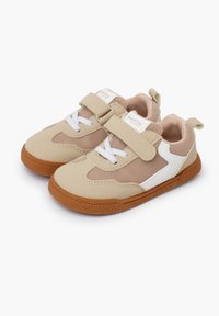 Zapatillas beige con paneles de malla, detalles en blanco y una correa de velcro. Cuenta con una suela de goma texturizada y cordones para un ajuste seguro.