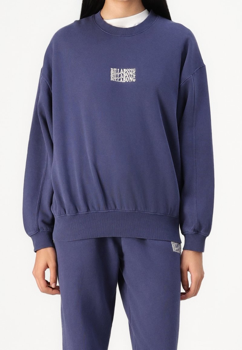 Marineblauwe sweatshirt van zacht materiaal, met een geribbelde halslijn en mouwen, en een klein Billabong-logo op de borst.