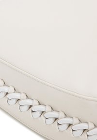 Cojín de cuero blanco con una superficie lisa y detalles intrincados tejidos en blanco a lo largo de un borde, destacando un diseño minimalista.