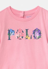 Camisa de algodón rosa con diseños florales dentro de letras navy que deletrean "Polo" en el pecho.