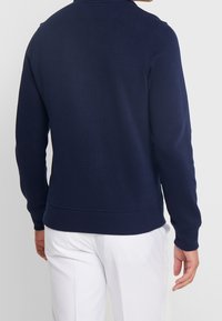 Mörkblå sweatshirt med ribbad textur, rundad halsringning och långa ärmar; har en klassisk passform samt elastiska muddar och nederkant.