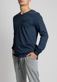 Marine gestreept langemouwen shirt met een V-hals en zak; gecombineerd met grijze sweatpants met een trekkoord. Zacht materiaal, casual pasvorm.
